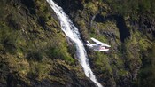 A seaplane flying next to a waterfall