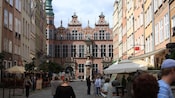 A historical town square featuring multistory buildings, a palace and a statue on a pedestal