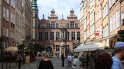 A historical town square featuring multistory buildings, a palace and a statue on a pedestal