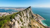 A rocky cliff dividing a coastline on one side and a city on the other