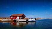 Un pequeño barco atracado junto a una cabaña en la costa