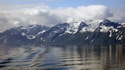 A body of water near a forest and mountains
