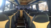 An aisle separates a row of 2 seats and a row of 1 seat with 4 seats across the back in a minibus