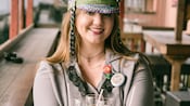 A woman in a decorated captain hat holding a tray of drinks