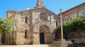 A stone cross standing near the entrance of a stone Gothic church