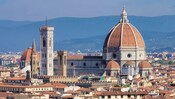 The cityscape of Florence, Italy, reveals a domed cathedral and 3 bell towers