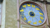 A bell tower featuring an astronomical clock with symbols of the zodiac on its dial