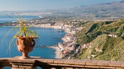 Una terraza de piedra con vista a un pueblo costero siciliano