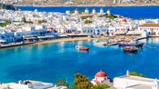 Una colina con cinco molinos de viento rodeada de resorts, cafés, tiendas y playas