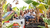 A group of people in an open air tour bus with a logo that reads Kauai Safaris