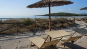 2 beach chairs, a table and straw umbrella overlooking an ocean