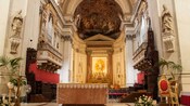 The interior of a domed church with multiple sculptures, frescos and ornate decorations