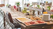 A table set for a large group reveals condiments and platters of bread, cheese and deli style meats