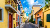 Una calle estrecha, rodeada de arquitectura con techos de tejas, puertas de madera y balcones de hierro fundido