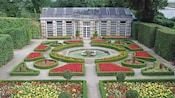 Una fuente, jardines y setos cerca de la casa de una hacienda
