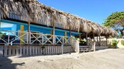 A beach house with a palapa roof and an open air dining area