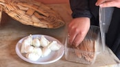 A woman's hand reaching for a utensil next to a plate filled with fresh mozzarella