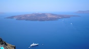 Um navio de cruzeiro navega próximo a uma ilha vulcânica