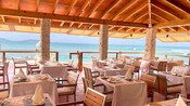 A shaded outdoor dining area next to a sandy beach