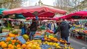 Um mercado de fazendeiros ao ar livre com vendedores que vendem frutas e vegetais