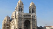 The neo Byzantine façade of a large limestone church reveals multiple domes, crosses and arches