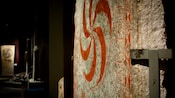 A museum display featuring a stone wheel with a circular Viking symbol