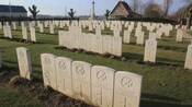 A military graveyard with a series of tombstones with crosses