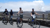 Bicyclists pause at the safety rail overlooking a volcanic crater