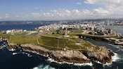 A lighthouse on a rocky coastline next to a city