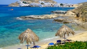 Thatched beach umbrellas near the shoreline of a Greek island