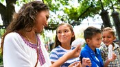 A family shares a fun moment in a park with large trees