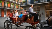 A family rides a horse drawn carriage amid low rise hotels in New Orleans
