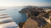 A Disney cruise ship surrounded by dramatic coastal cliffs