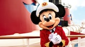 Minnie Mouse standing on deck of a cruise ship while wearing her captain's hat and outfit