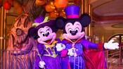 Ready for Halloween, Mickey Mouse in a vampire costume and Minnie Mouse in a witch costume standing arm in arm