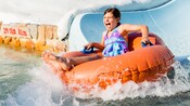 A little girl slides down into the water on an innertube 