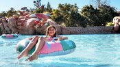 A smiling young girl sits in an inner tube in Melt-Away Bay in Disney's Blizzard Beach