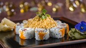 Des sushis placés en cercle sur une grande assiette avec une fleur sur le côté