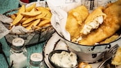 A fish and chips meal is wrapped in paper that reads Cookes of Dublin Finest Fish and Chips Established 1938