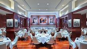 Um salão de jantar com mesas postas de maneira formal e fotos do Miami Dolphins nas paredes