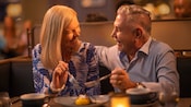 A man and woman smile at each other while sharing a dessert