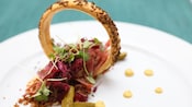 Corned beef presented inside a rye cracker ring, accented with mustard and pickles