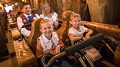 2 girls smile on a roller coaster with a woman and a Guest Services Member