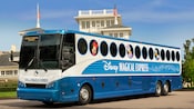 Com imagens do Mickey, Minnie, Donald e Daisy, o ônibus do Disney’s Magical Express situa-se em frente a diversos edifícios do Walt Disney World Resort