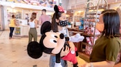 A young girl holding an oversized Mickey plush inside the Emporium at Magic Kingdom park