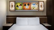 Chambre de choix avec œuvre d’art éclairée présentant des personnages Disney animés, au-dessus d’un lit