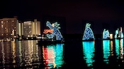 A sea monster made of lights on a lake near a hotel