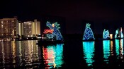 A sea monster made of lights on a lake near a hotel