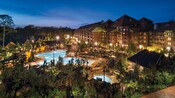 Alpine trees surrounding a multistory wood and stone wilderness lodge with an impressive pool area 