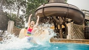A girl slides into a pool with a large splash